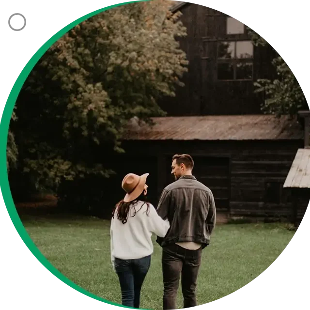 A man and woman holding hands while walking in the grass.